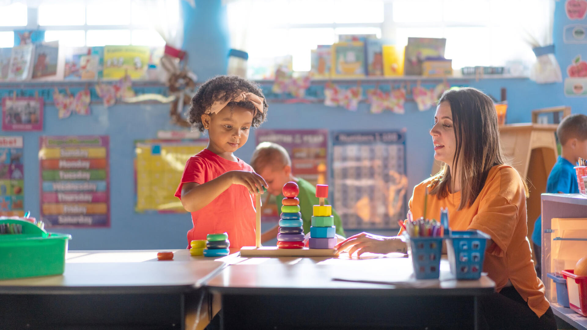 A preschool girl is actively learning and growing under the guidance of her teacher in a nurturing daycare environment
